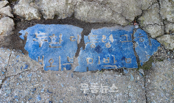 망월동 5·18 유공자 및 민족민주열사묘역 입구에는 대리석으로 된 표지석 하나가 땅바닥에 처박혀 있다. 그리고 오늘도 묘역을 찾는 참배객들의 발에 짓밟혀 닳아서 훼손되어 없어질 위기에 있다.